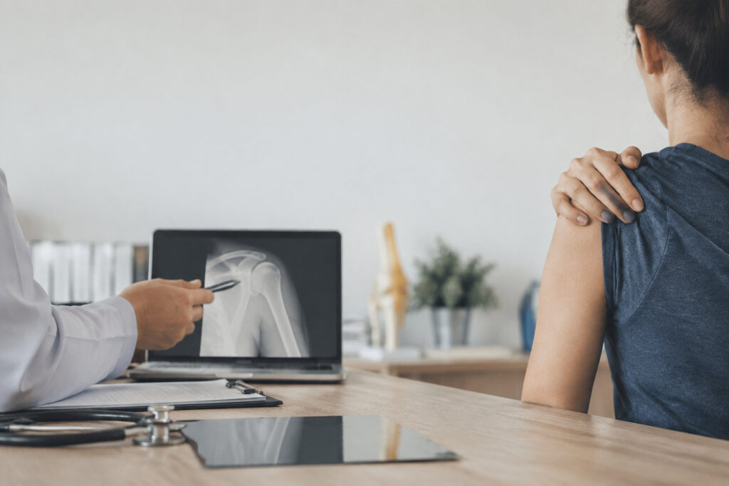Un médecin montre une radiographie de l'épaule à une patiente lors d'une consultation médicale.